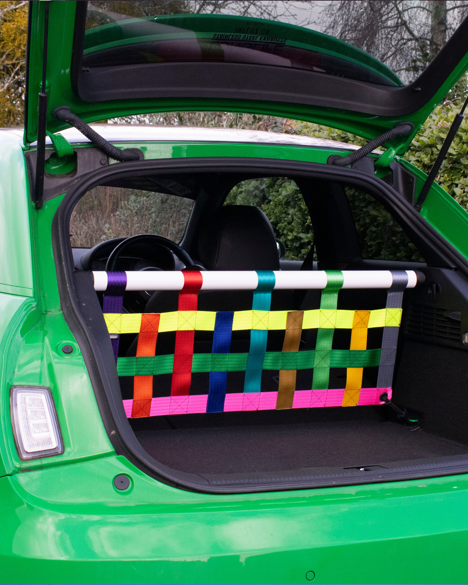 White bar with multicoloured cargo net installed in a green Audi A1.