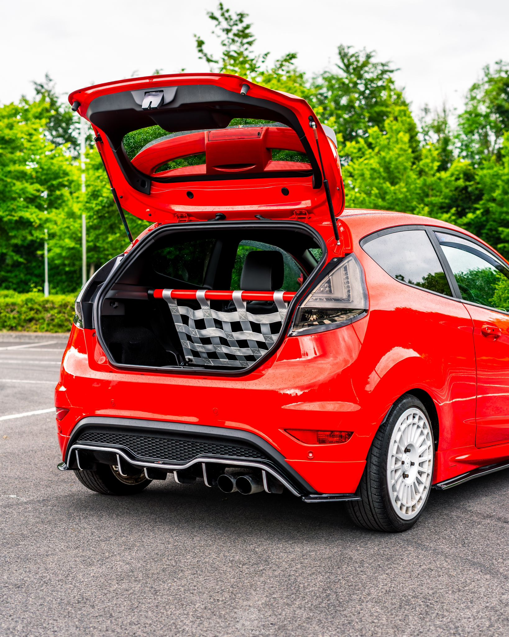 Red Ford Fiesta Mk7 with a rear seat delete floor, red bar and grey cargo net installed